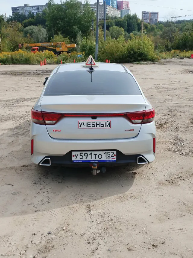 Учебный Kia Rio с табличкой «Учебный» над номером, вид сзади