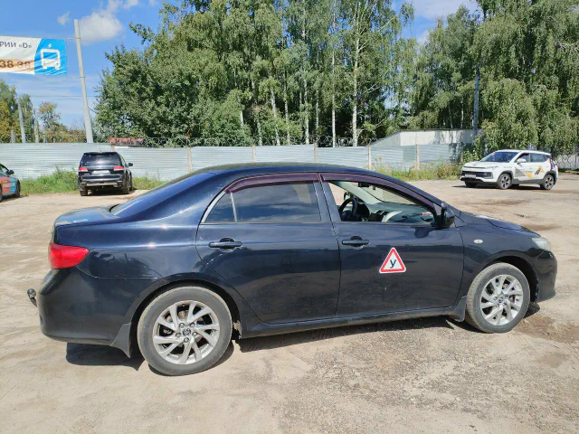 Тёмно-синий учебный Toyota Corolla на площадке, вид сбоку