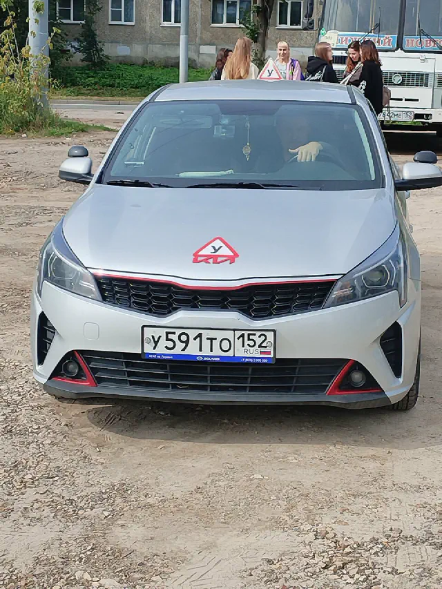 Серебристый учебный Kia Rio с табличкой «У» на крыше, вид спереди