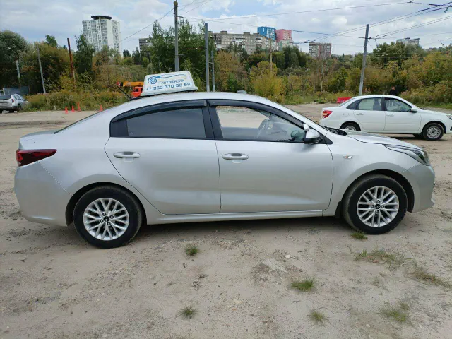 Серебристый учебный Kia Rio с крышевым знаком «Автошкола», вид сбоку