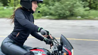 Девушка в шлеме на учебном мотоцикле Bajaj Boxer