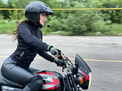 Девушка в шлеме и экипировке на учебном мотоцикле Bajaj Boxer
