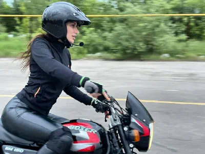 Девушка в шлеме и экипировке на учебном мотоцикле Bajaj Boxer
