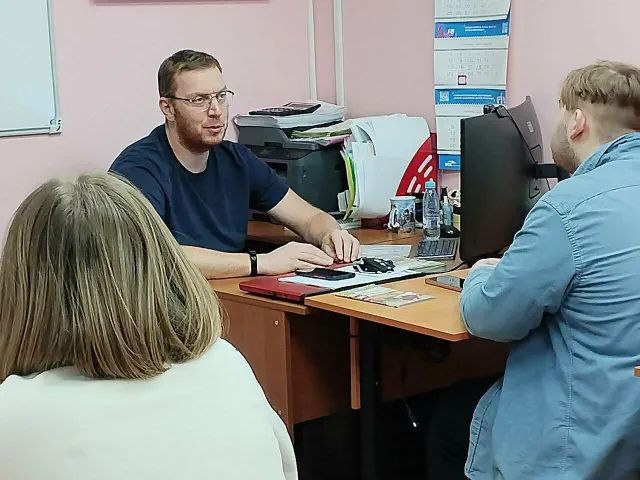 Разговор за рабочим столом в офисе автошколы